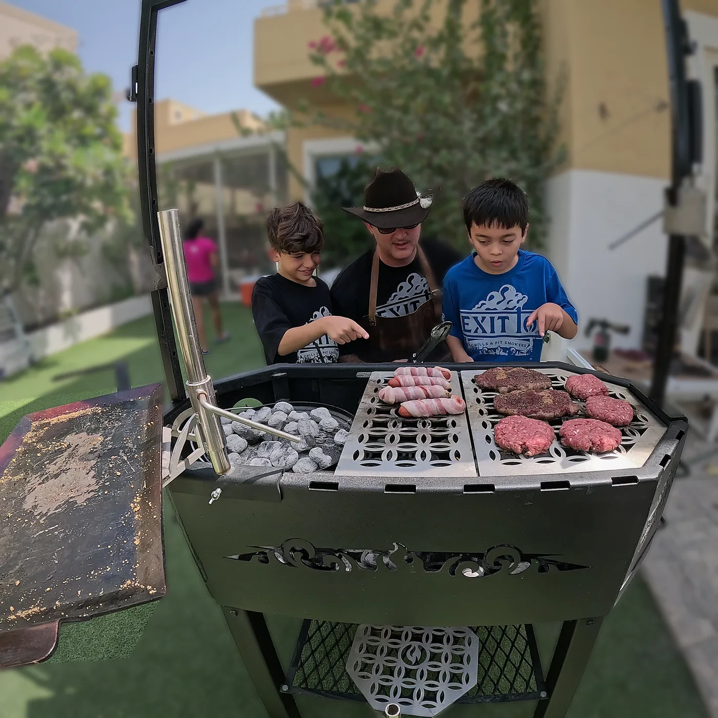 Pitmaster Hunter and the boys grilling burgers, steaks and bacon-wrapped sausages on the Exit 10 Reaper in the backyard